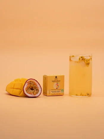 Embalagem de 3 pastilhas Solid Drink Bio sabor manga e maracujá da Qwetch com manga fatiada, maracujá aberto e copo de bebida com gelo e sementes.